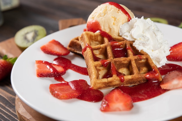 Waffle with strawberries, vanilla ice cream and whipped cream
