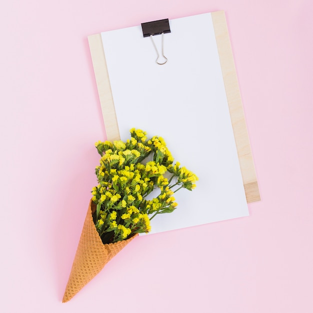 Waffle with yellow flowers over the clipboard over pink backdrop