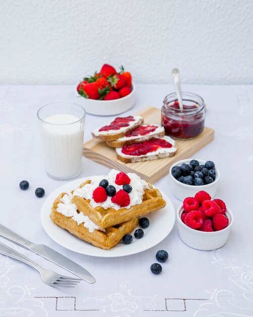 Waffles, milk and berry fruits on table