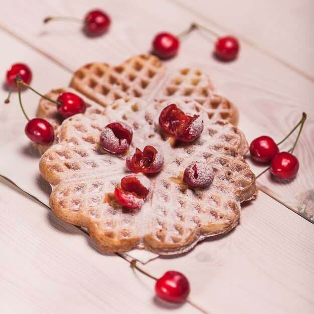 Waffles with cherry on white wooden plank