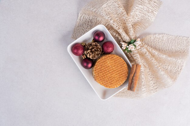 Waffles with cinnamon and Christmas toys on white plate 