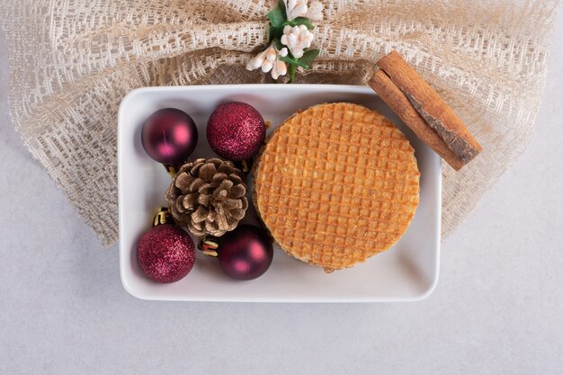 Waffles with cinnamon and Christmas toys on white plate 