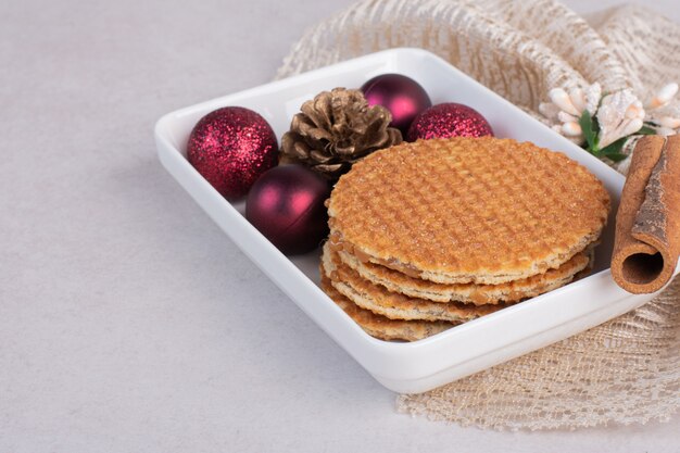 Waffles with cinnamonnd Christmas toys on white plate .