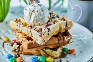 Free photo waffles with ice-cream, chocolate, chocolate balls on the white plate with tea