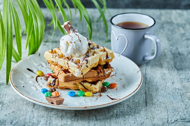 Foto gratuita cialde con gelato, cioccolato, palline di cioccolato sulla piastra bianca con tè