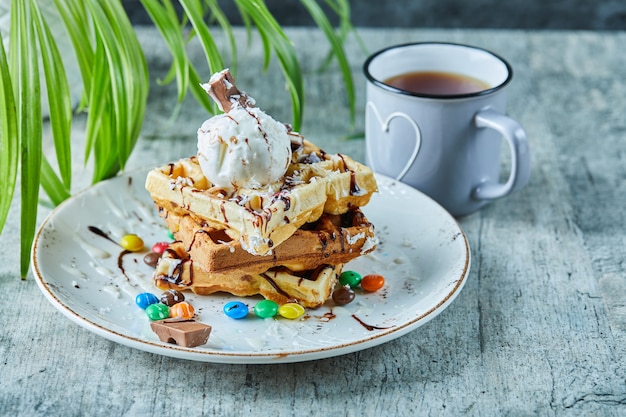 お茶と白い皿にアイスクリーム、チョコレート、チョコレートボールとワッフル