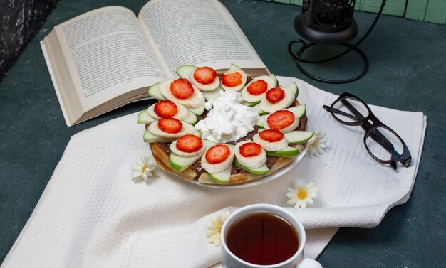 Waffles with sliced banana, strawberries and whipping cream