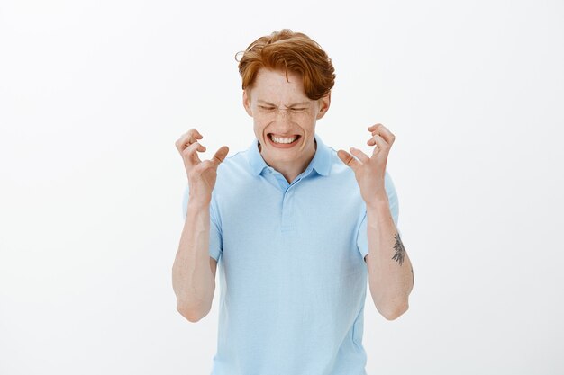 Waist-up portrait of annoyed and pissed-off, angry redhead man clenching fingers bothered