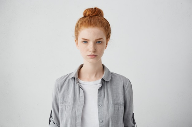 Waist up portrait of beautiful European 20 y.o. woman with freckles and hair knot posing isolated