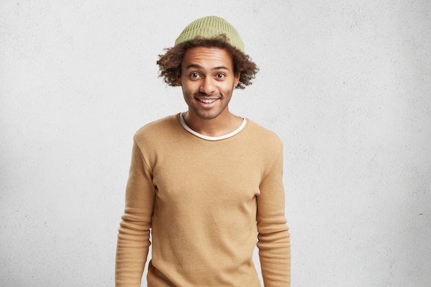 Free photo waist up portrait of dark skinned funny male wears hat and sweater, poses