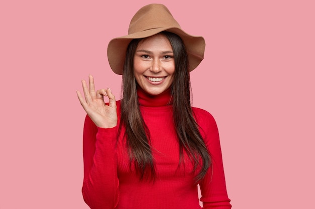 Waist up portrait of good looking girlfriend shows okay gesture, shows agreement, gives approval