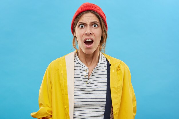 Waist up portrait of shocked or frustrated fashionable young woman, having puzzled and surprised expression on her face. Funny girl opening mouth in shock and astonishment