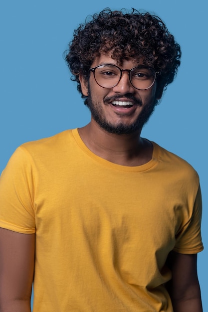 Free photo waist-up portrait of a smiling pleased guy in round spectacles looking in front of him