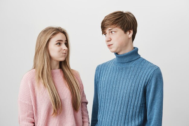不満を持つニットのカラフルなセーターを着ている若い女性と男性の上半身の肖像画が頬をふくれっ面に見える