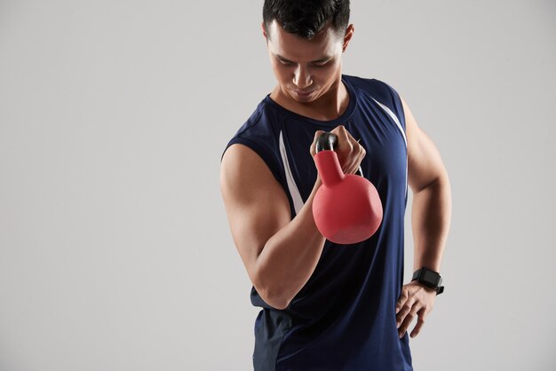 Waist up portrait of young powerlifter posing with weght looking down