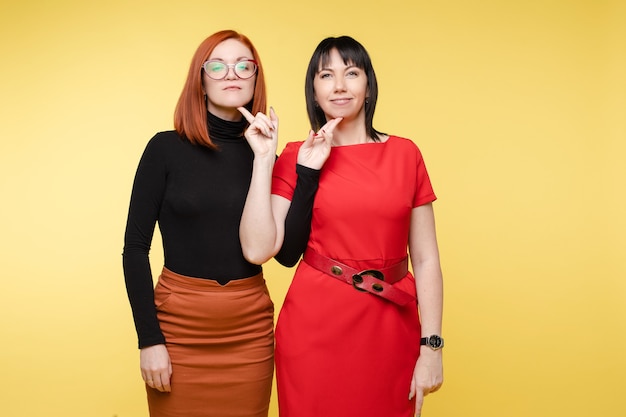 Free photo waist up of pretty ladies touching by fingers chins each other. isolated on yellow background