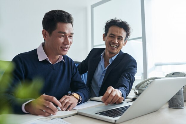 Waist up shot of business men surfing the net on laptop togther