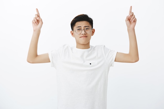 上向きの手を上げる丸いメガネの一般的なハンサムなアジアの少年のウエストアップショット