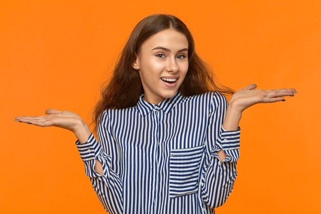 Waist up shot of emotional excited young female in good mood smiling broadly