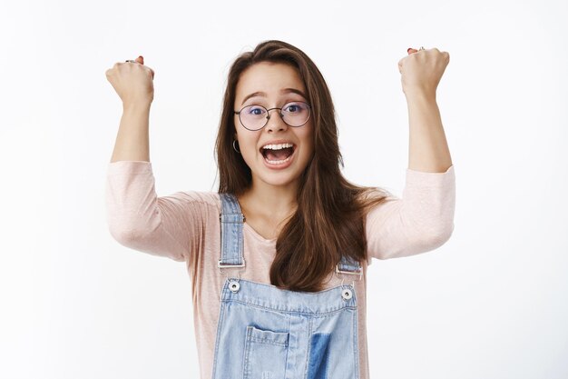 Waist-up shot of excited happy triumphing woman in glasses yelling yes in support and amazement as feeling joyful of gaining goal