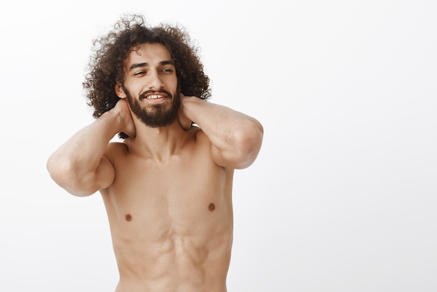 Waist-up shot of good-looking confident curly-haired guy with beard