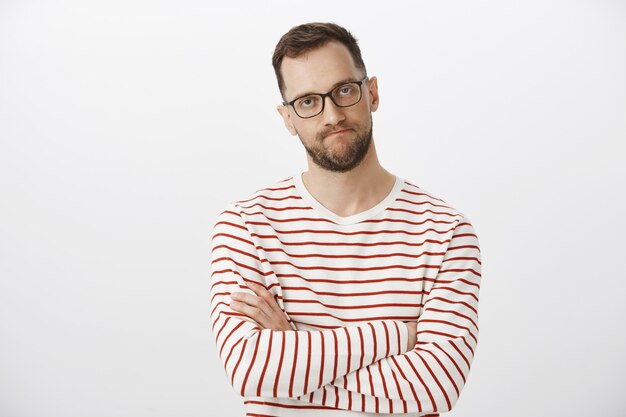 Waist-up shot of intense pissed off european entrepreneur in black glasses, crossing hands on chest and clenching lips