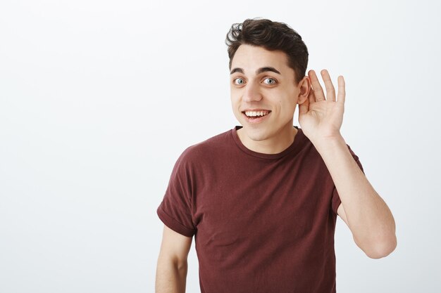 Waist-up shot of intrigued charming happy guy in red t-shirt