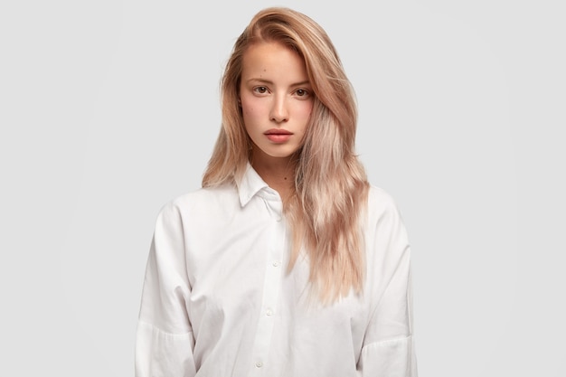 Waist up shot of serious Caucasian female with straight luxurious hair models in studio