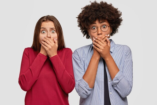 Снимок шокированных удивленных женщин, прикрывающих рот обеими руками