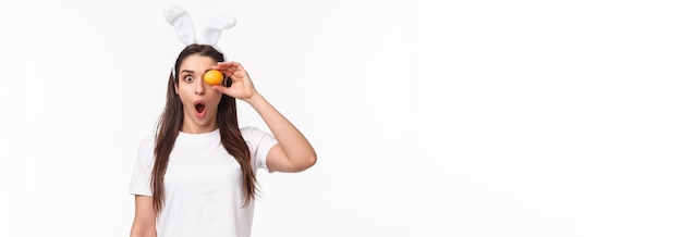 Waistup portrait of amazed and surprised young woman seeing something awesome hold colored egg over