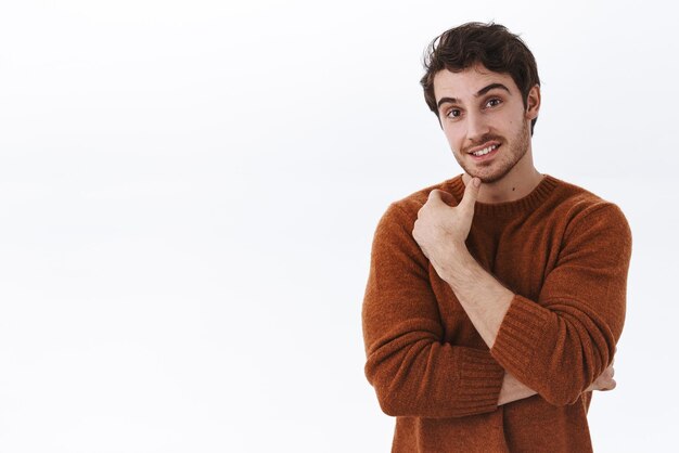 Waistup portrait of interested handsome young male listening curious news smiling and looking intrigued touching chin thoughtful consider buy something use company service white background