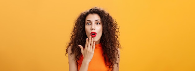 Free photo waistup shot of amazed and excited caucasian woman with curly hair in red lipstic opening mouth from