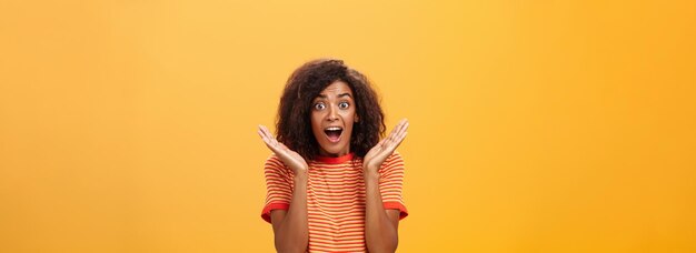 Waistup shot of amazed joyful sociable darkskinned female with afro hairstyle in striped tshirt