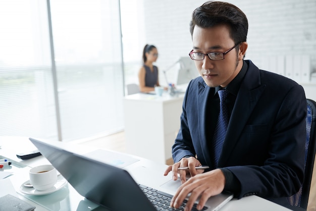 Coworking 공간에서 노트북에서 일하는 아시아 사업가의 허리 샷