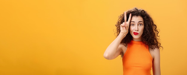 Free photo waistup shot of charismatic goodlooking european female with curly haircut in cropped top showing pe