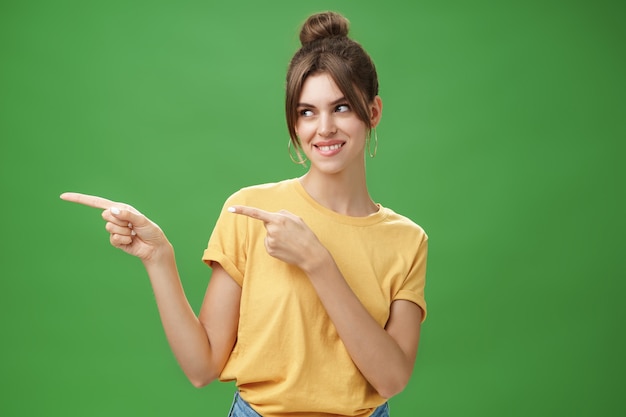 Waistup shot of charismatic happy and carefree charming woman in yellow tshirt pointing and looking ...