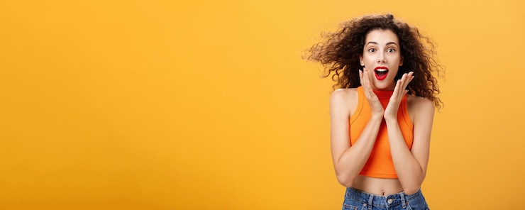 Free Photo waistup shot of charmed enthusiastic attractive female with curly hairstyle in cropped top holding p