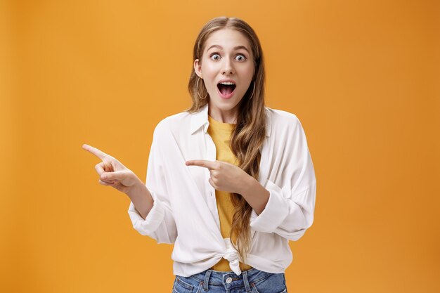 Waistup shot of excited speechless impressed young cute woman with curly hair dropping jaw from amaz...