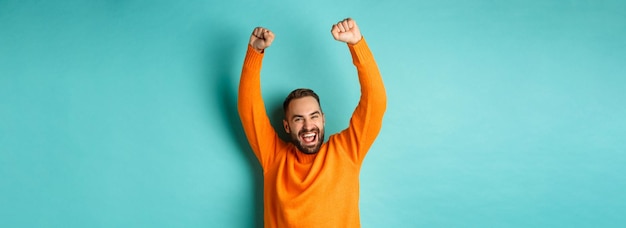 Free photo waistup shot of happy guy triumphing raising hands up and rejoicing of winning celebrating victory s