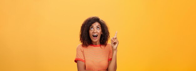 Waistup shot of interested curious goodlooking darkskinned female in striped tshirt talking asking