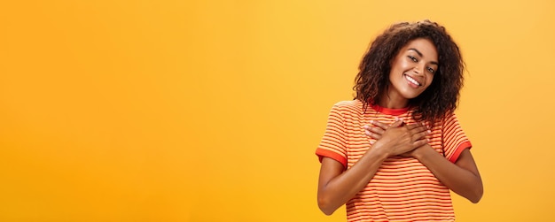 Бесплатное фото Снимок талии очаровательной чувственной темнокожей женщины с кудрявой прической в модной футболке, держащей приятеля