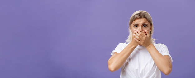 Free photo waistup shot of shocked nervous and scared young woman witnessing terrible crime covering mouth with