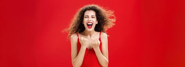 Foto gratuita colpo in vita di una donna felice soddisfatta e felice di successo con i capelli ricci in abito elegante