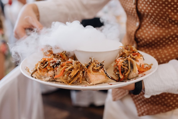 Waiter carries a plate with delicacy portion meal