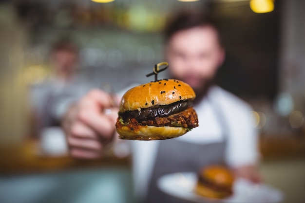 Waiter holding a burger with tong