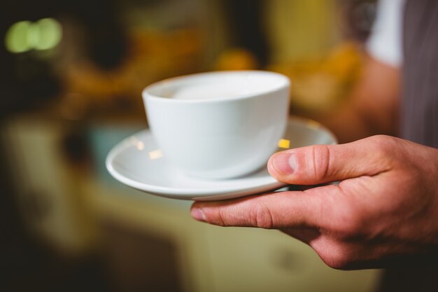 Waiter holding cup of coffee in cafÃ©