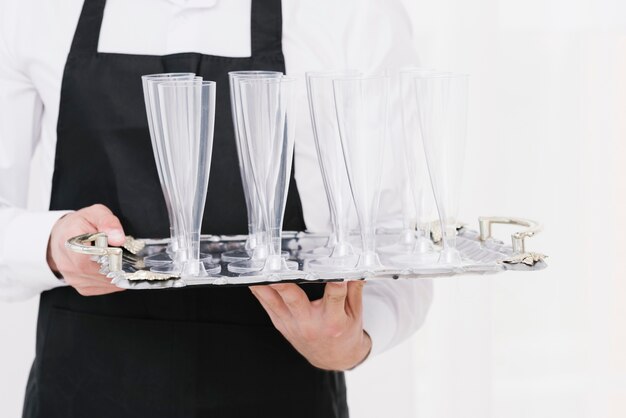 Waiter holding empty glasses on a tray