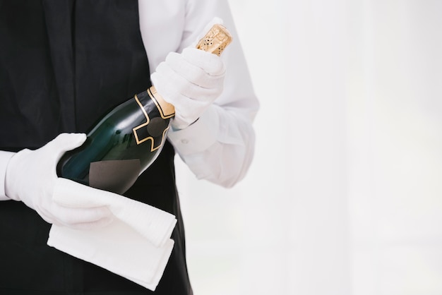 Бесплатное фото Официант в форме, представляя шампанское