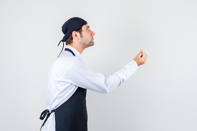 Waiter looking up and making italian gesture in uniform, apron and looking confident. .