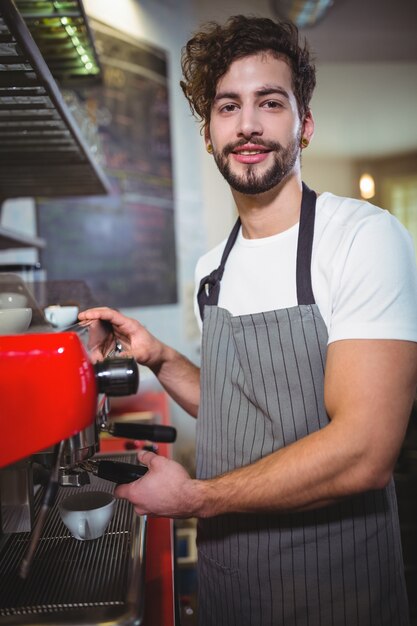 Waiter making cup of coffee at counter in kitchen